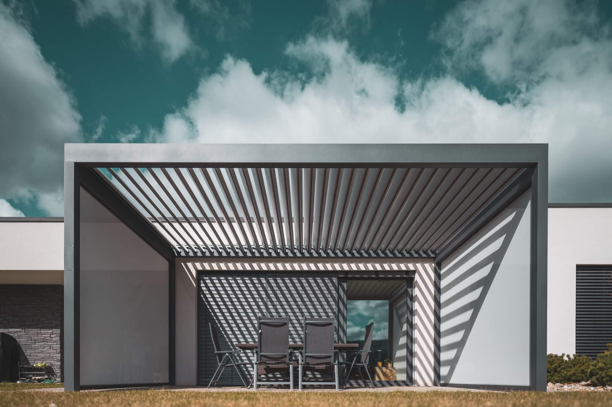 Minimalistická hliníková pergola s lamelovou strechou pri modernom dome